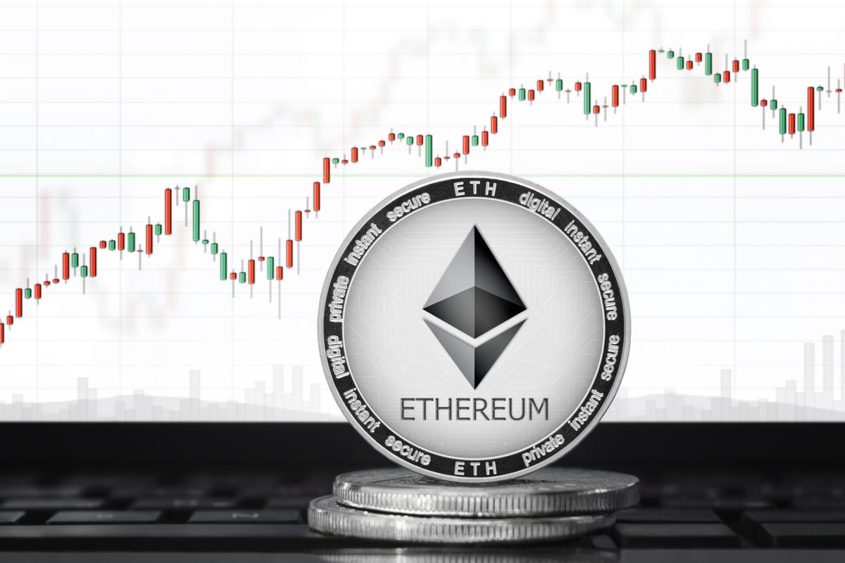 Picture of an ethereum coin standing on two other coins with a candlestick price chart behind it