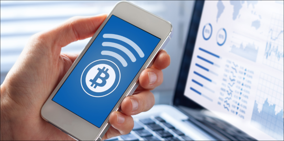 Picture of a hand holding a mobile phone with a bitcoin logo on it